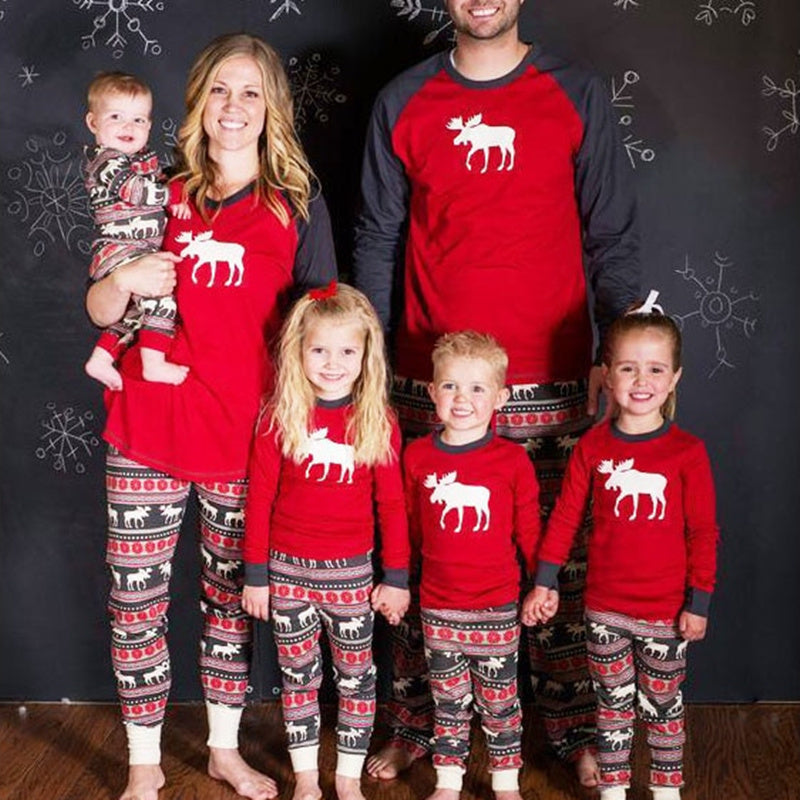 Family of five wearing matching red pajamas with moose design against a black background.
